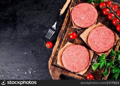 A raw burger on a tomato cutting board. On a black background. High quality photo. A raw burger on a tomato cutting board.