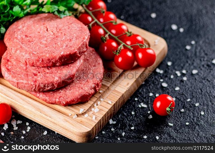 A raw burger on a tomato cutting board. On a black background. High quality photo. A raw burger on a tomato cutting board.