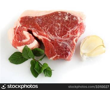 A raw lamb chop with garlic and mint, over a white background with a faint shadow