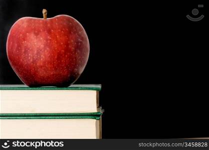 A red apple red on a green book on a black background