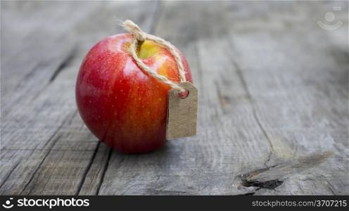 A Red Apple with a Price Label on wood background