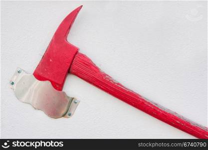 A red axe hanging on a white wall