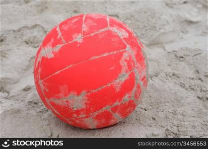 A red ball volleyball on beach sand
