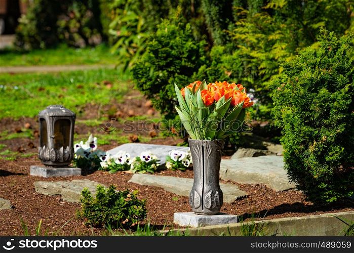 a red candle on the tombstones with flowers