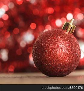 A red christmas bauble on the background of red boken