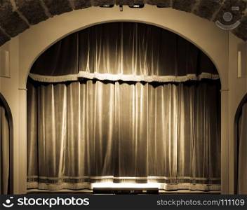 A red curtain in an old and very small Italian theatre.