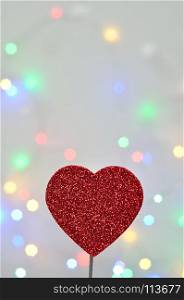A red glitter heart isolated against an out of focus light background
