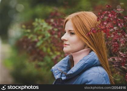 A red-haired girl walks among the beautiful bushes.. A girl in nature among the bushes 2744.