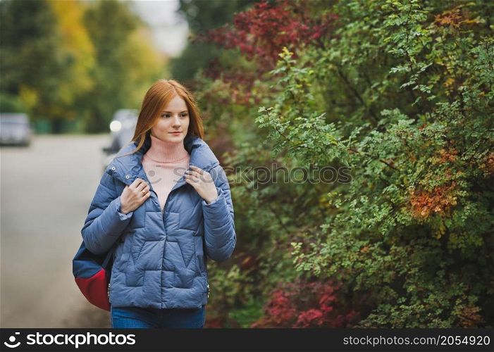 A red-haired girl walks among the beautiful bushes.. A girl in nature among the bushes 2747.