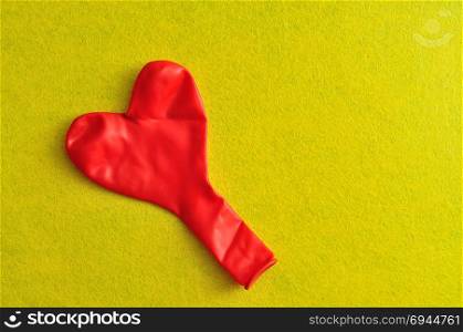 A red heart shape balloon on a yellow background
