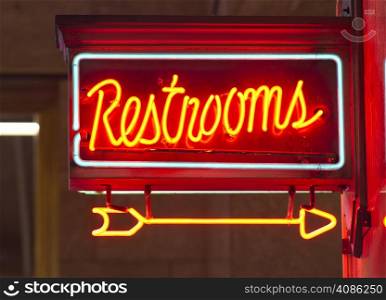 A red neon sign points the way to the restrooms