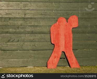 A red plywood shape in the form of a lacrosse goalie that is leaning up against a green backstop is used for target practice by the team.