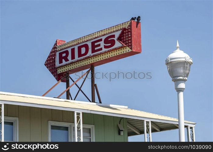 A red sign with arrow pointing at the boardwalk where carnival rides are available
