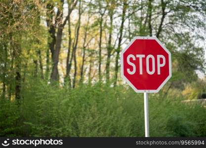 A red stop sign in front of a small patch of forest