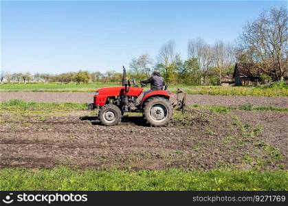 A red tractor on which a farmer sits and cultivates the land for further planting and sowing. A red tractor on which a farmer sits and cultivates the land for further planting and sowing.