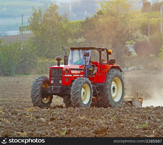 A red tractor working on a field