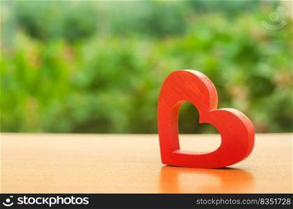 A red wooden heart on nature background. The secret of relationships and the rules of a strong family. Strong love affair. Secrets, rumors and gossip. concept of female intimate health. Heart health