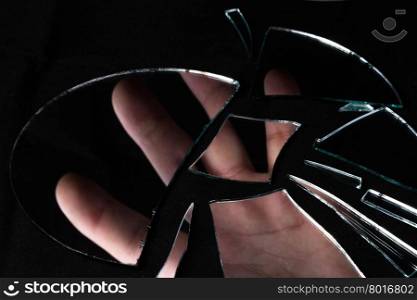 a reflection of the man&rsquo;s hand in pieces of broken mirror on a black background