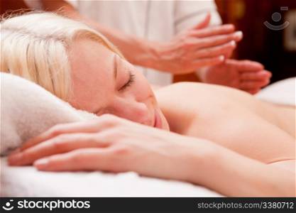 A relaxed blond woman receiving a percussive massage in a spa