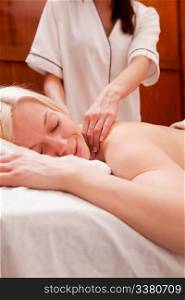 A relaxed peaceful woman receiving a shoulder massage at a spa