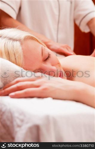 A relaxed woman receiving a back massage in a spa