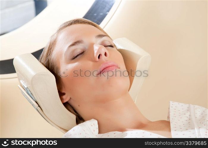 A relaxed woman with eyes closed ready for a CT scan
