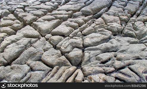 A relief or pattern with gutters, cracks and crevices in a gray granite rock at the Seychelles. Created by the tides, rain water and erosion. A consolidated structure texture from ditches and depressions. Rock and stone structures with gutters, cracks and crevices formed by water from the sea and the rain