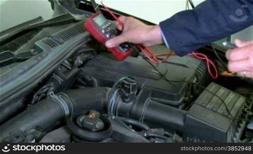 A repairman checking the electrical current with a voltmeter.Car reparation and test.A mechanic testing the electrical system of a car.