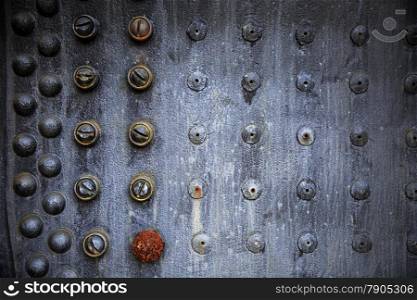 A repeating pattern of rusting rivets on the outside of an old steam engine locomotive forms a unique background.