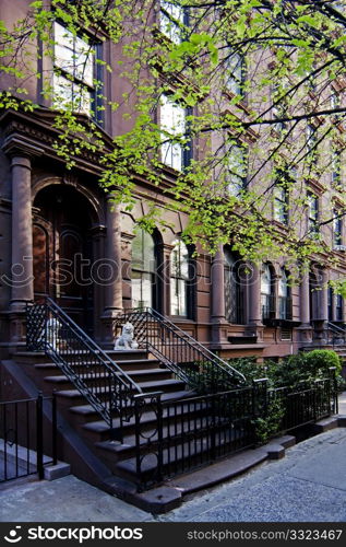 A residential New York, Philadelphia, Boston or Chicago brownstone townhouse building with balck fence and steps in front.