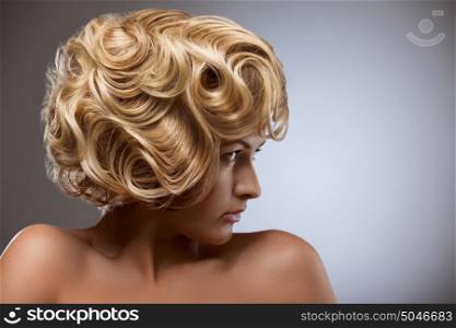 A retro photo of a sensual blond woman with a curly vintage hairstyle.
