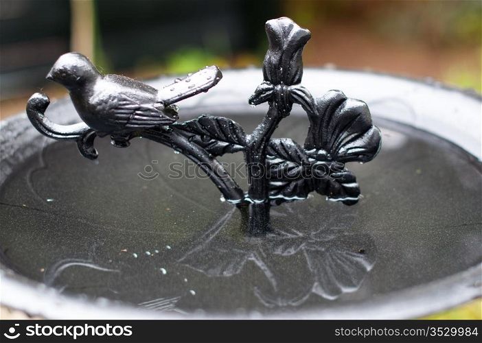 A richly decorated metal birdbath in a garden