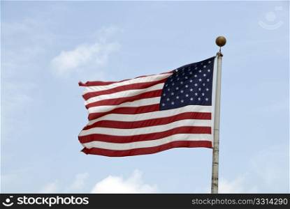a ripped american flag fluing high with the wind
