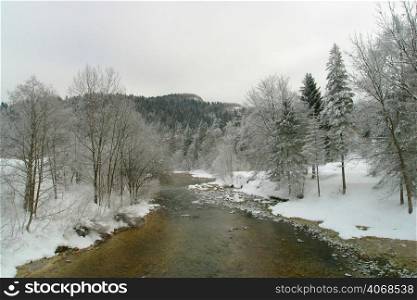 A river meanders through the snow covered ground, Bled, Slovenia.