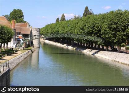 a river with its bridge rainbow sky surrounded by trees in the town of Montargis