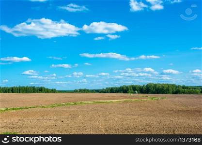 A road through the plowed field on a Sunny summer day.
