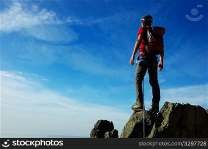 A rock / mountain climber at the summit of his climb, basking in brilliant sunshine. West Alps, Italy.