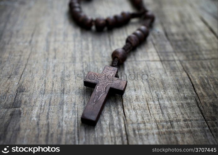 A rosary with beads on wooden textured background.