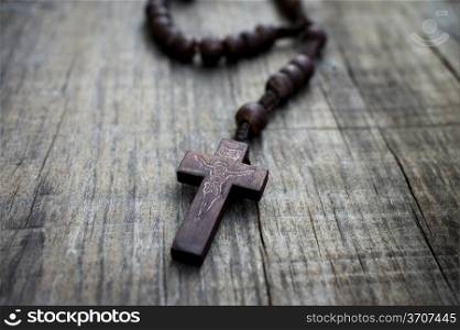 A rosary with beads on wooden textured background.
