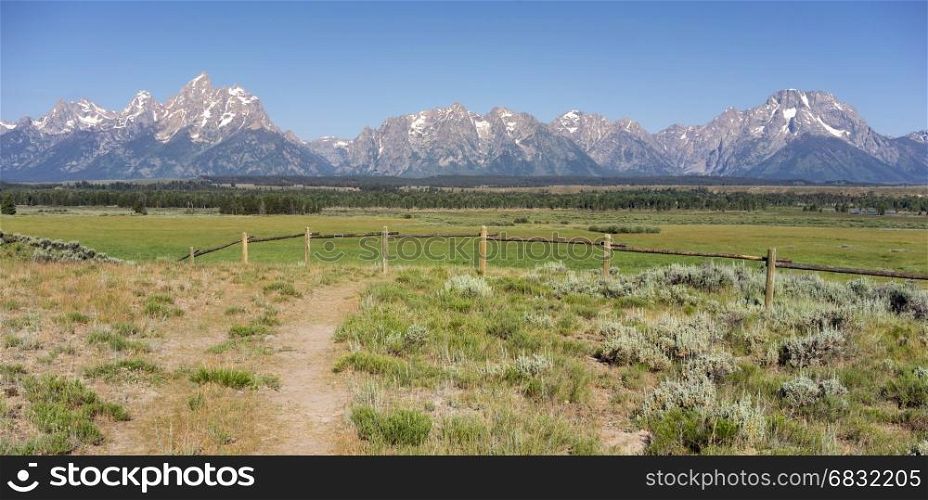 A rough trail leads over to the fence line in view of the Rocky Mountains