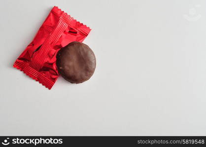 A round biscuits covered in chocolate with a red wrapper