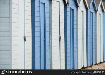 A row of alternate dark and light blue beach huts by the seaside