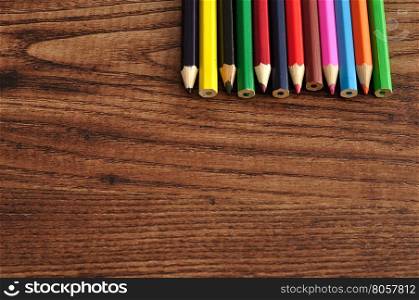 A row of colorful coloring pencils displayed on a wooden background