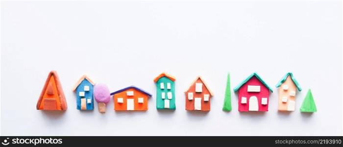 a row of rustic colorful cute houses and trees made of plasticine. isolate on white background.