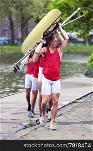 A rowing team carrying their boat to the boat house after a race