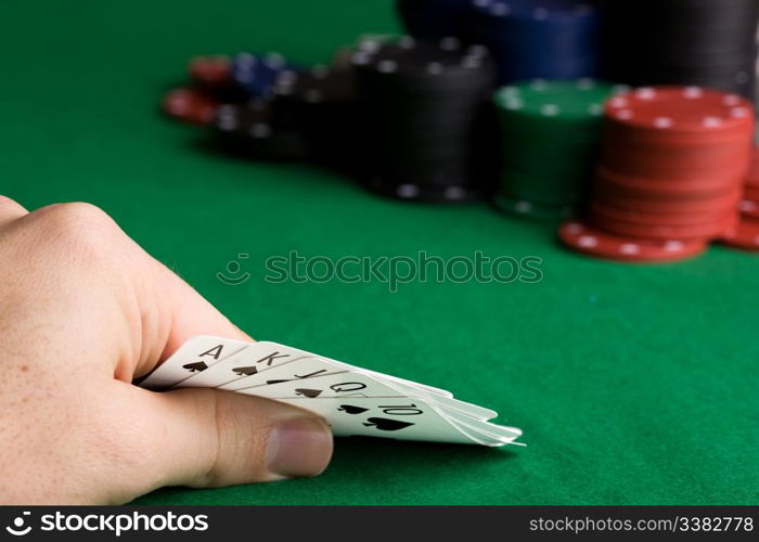 A royal flush in spades with poker chips in the background