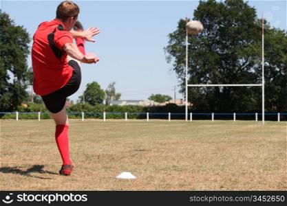 A rugby player kicking a ball