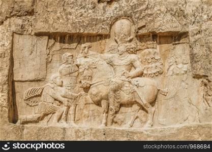 A ruin and ancient Sassanid rock relief depiction of the triumph of Shapur I over the Roman emperors Valerian and Philip the Arab, Naqsh-e Rostam, Fars Province. Shiraz, Iran.