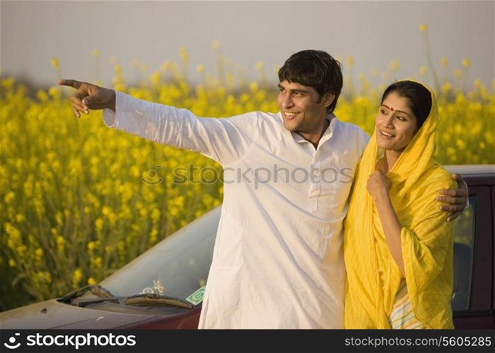 A rural couple in front of their car