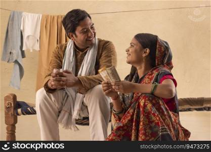 A RURAL COUPLE LOOKING AT EACH OTHER WHILE COUNTING MONEY